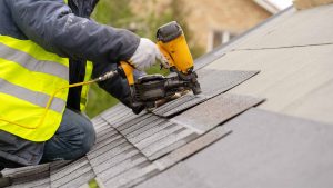 Man installing shingles on new roof